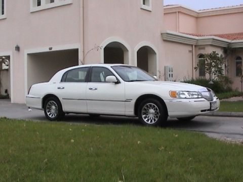 2002 Lincoln Town Car - A white 2002 Lincoln Town Car is seen from a three-quarter front view, parked on a grassy area in front of a residential building.