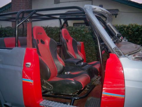 1985 Ford Bronco - The interior of a modified SUV features racing bucket seats and a prominent roll cage structure.
