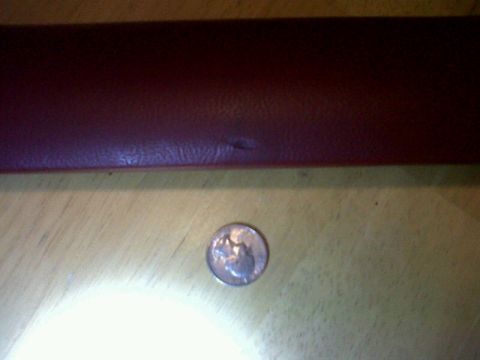 1989 Ford Bronco - A close-up view of a maroon interior trim piece and a coin, with a watermark for Supermotors.net.