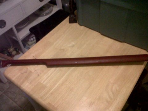 1989 Ford Bronco - This is a dark red interior trim piece, likely from a vehicle's dashboard or door panel, shown on a wooden surface.