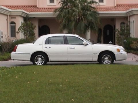 2002 Lincoln Town Car - Side view of a white 2002 Lincoln Town Car parked in front of a house.