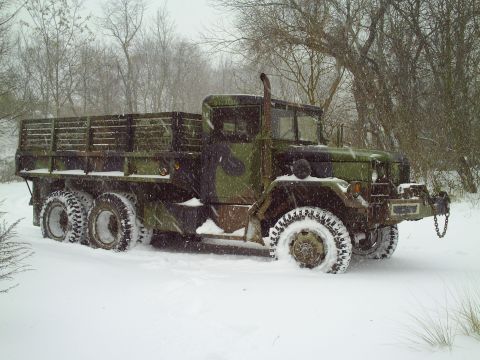 1990 Ford Bronco - A military truck with camouflage paint is stuck in the snow during a winter storm.