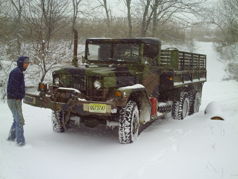 guy next to camo military truck in snow