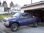 1988 Suzuki Samurai - A purple Nissan Hardbody pickup truck is parked in a driveway next to an open garage.