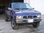 1988 Suzuki Samurai - This blue pickup truck is shown from the front 3/4 angle. The license plate is visible.