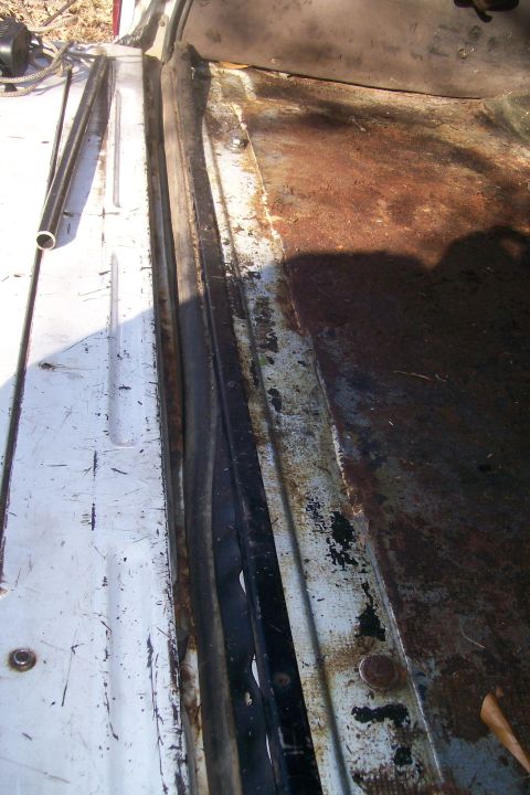 1992 Ford C-350 (Centurion Conversions) - The interior floor and door seal area of a white vehicle show significant rust and wear.