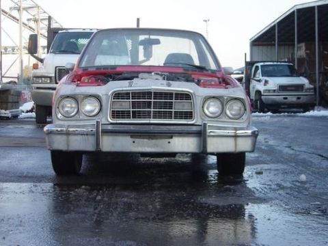 1972 Ford Ranchero - A car with its hood open is parked on wet ground, with other vehicles visible in the background.
