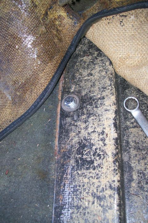 1992 Ford C-350 (Centurion Conversions) - Close-up of a bolt and a wrench on the floor of a vehicle, near carpet padding.