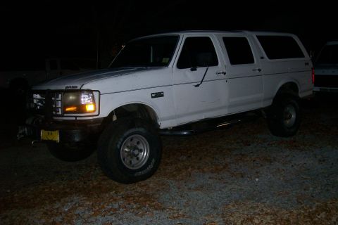 1992 Ford C-350 (Centurion Conversions) - This modified SUV is parked outdoors at night, showing off its lifted suspension and off-road tires.