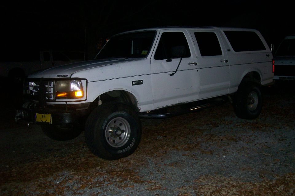 White SUV with a body lift, side view. It has a winch and a smiley face plate on the front