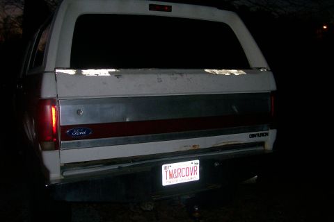 1992 Ford C-350 (Centurion Conversions) - Night rear view of a white Ford wagon-body tailgate with a red accent stripe, blue Ford oval, CENTURION badge on the right corner and surfa…
