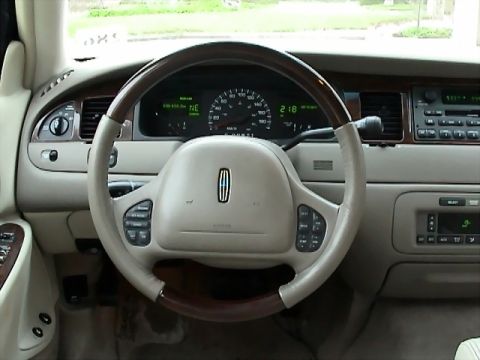 2002 Lincoln Town Car - The interior of a 2002 Lincoln Town Car shows a wood-trimmed steering wheel and a digital instrument cluster.