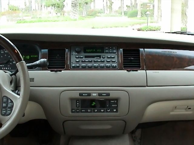 Tan luxury sedan dashboard with wood trim, radio and climate controls