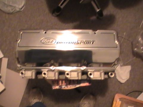 1971 Ford Mustang - A shiny Ford Motorsport valve cover is shown from above, resting on a carpeted surface.