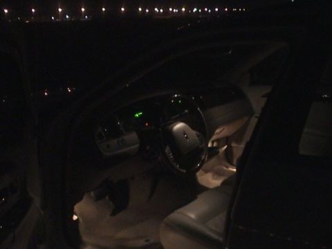 2002 Lincoln Town Car - The dimly lit interior of a car shows the dashboard and steering wheel, with a person's head visible.