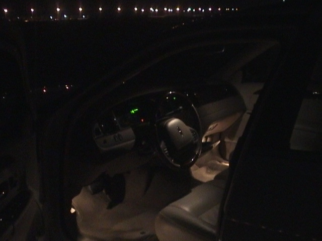 Dark night interior of a Lincoln Town Car, steering wheel and lit gauges