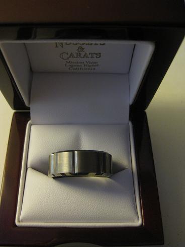 1990 Ford Probe - A brushed metal ring rests inside a dark wood jewelry box with the jeweler's name visible on the interior lid.