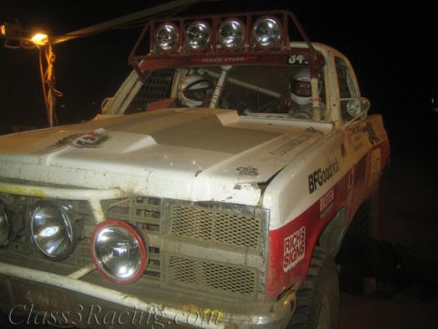 1986 Ford Bronco - This off-road race truck, modified for competition, is seen from the front-right angle at night.