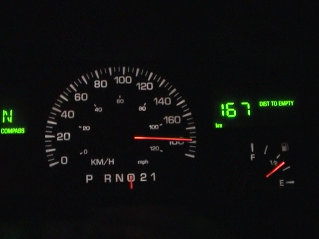 Night dash cluster with speedometer needle past the top of the scale and 167 km distance-to-empty