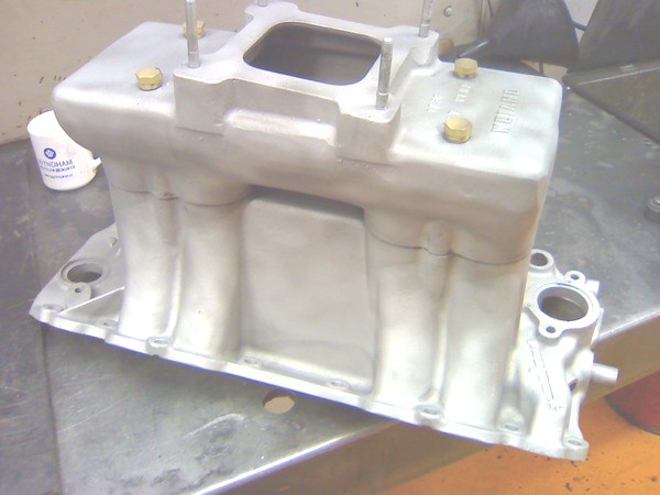 Bare aluminum Weiand tunnel ram intake manifold on a workbench