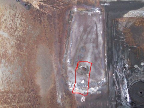 1969 Ford Torino - Close-up of a heavily rusted metal panel, likely from a vehicle's undercarriage, with a hole highlighted.