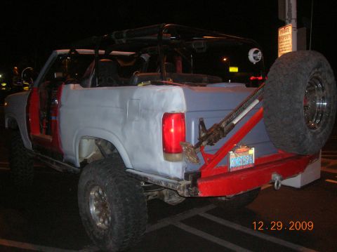 1985 Ford Bronco - This modified Ford Bronco shows a primer gray body with red doors and a red rear bumper, fitted with a spare tire.