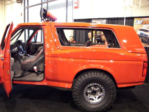 2006 Dodge 2500 - Orange SUV with roll cage and off-road lights on the roof is shown from the side.