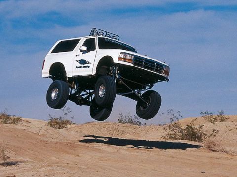 2006 Dodge 2500 - This modified Ford Bronco is airborne over a desert landscape.
