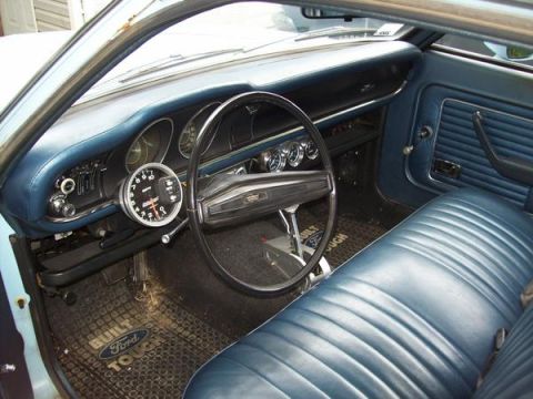 1973 Ford Maverick - The interior of a 1973 Ford Maverick features blue vinyl seats and a dashboard with a tachometer.