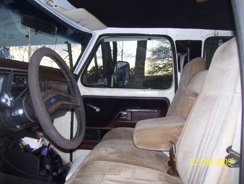 1978 Ford Bronco - The interior of a 1978 Ford F-350 crew cab features tan upholstery and wood-grain trim on the dashboard and door panels.