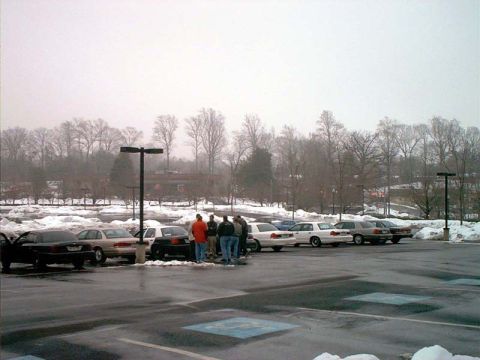 2000 Ford Crown Victoria - A group of people stand near several Ford Crown Victorias parked in a lot during winter.