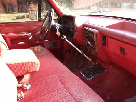1990 Ford F-150 - Interior view of a 1990 Ford F-150, a red bench seat and a prominent floor-mounted shifter.