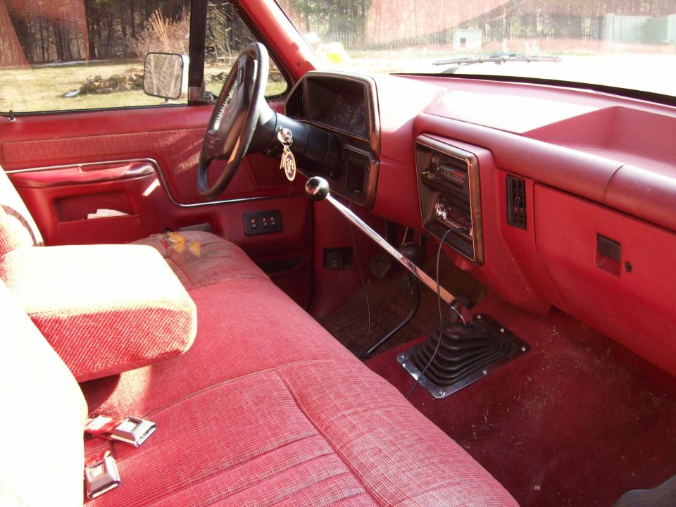 1990 Ford F-150 interior with red bench seat and floor shifter