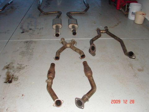 1995 Ford Bronco - Various exhaust system components, including mufflers and catalytic converters, are arranged on a concrete surface.