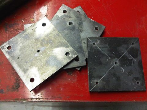 1996 Ford Bronco - A collection of metal plates, some with multiple holes, are arranged on a red workbench surface.