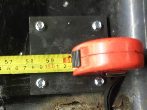 1996 Ford Bronco - A measuring tape is used to measure a metal plate that has been bolted to a surface.