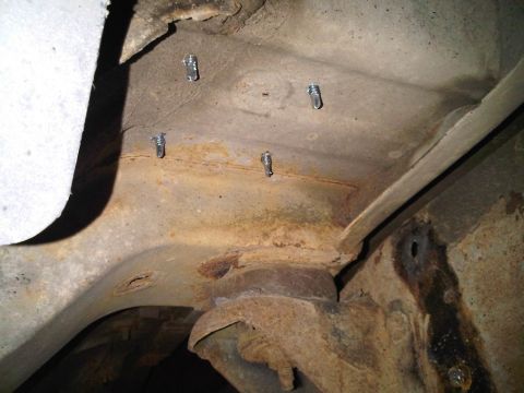1996 Ford Bronco - The underside of a vehicle shows a rusty frame with newly installed bolts, possibly for a cage build.