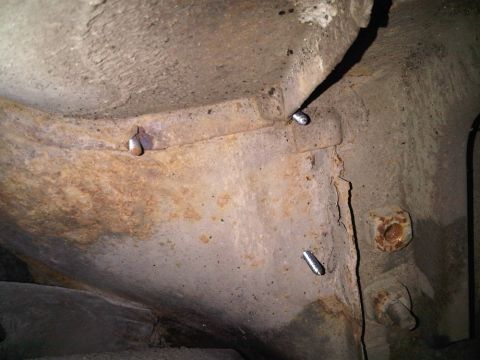 1996 Ford Bronco - Close-up view of rusted metal frame components with visible bolts and nuts.