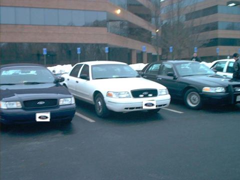 2000 Ford Crown Victoria - Three Ford Crown Victoria sedans are parked in a lot outside a modern office building.