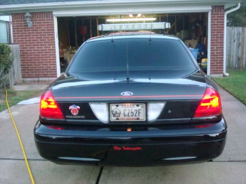 2003 Ford Crown Victoria - Rear view of a black 2003 Ford Crown Victoria, equipped with a light bar and displaying a Texas license plate.