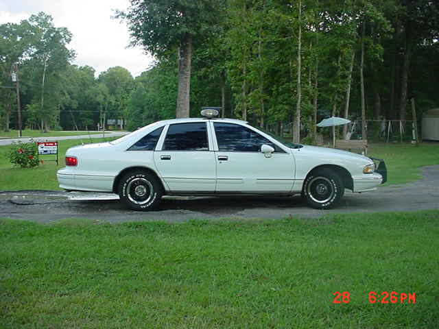 Side view of a white sedan with a light bar on the roof