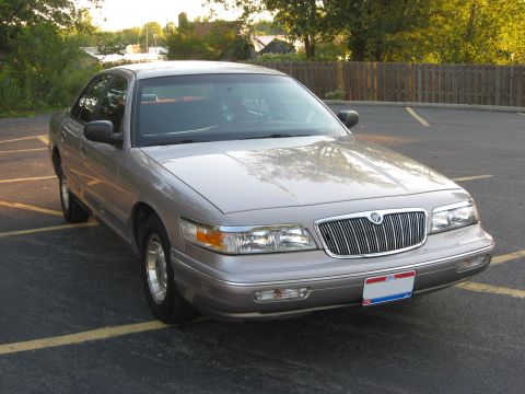 1995 Mercury Grand Marquis - This 1995 Mercury Grand Marquis is parked in a lot with a wooden fence in the background.