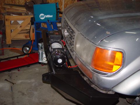 1993 Ford Bronco - Aftermarket bumper with winch mounted on a grey SUV, with a Miller welding machine in the background.