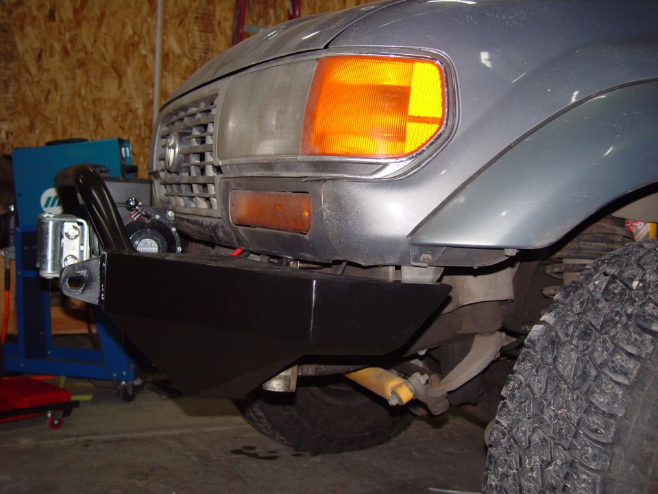 Front view of a gray Toyota Land Cruiser with an aftermarket black bumper and winch