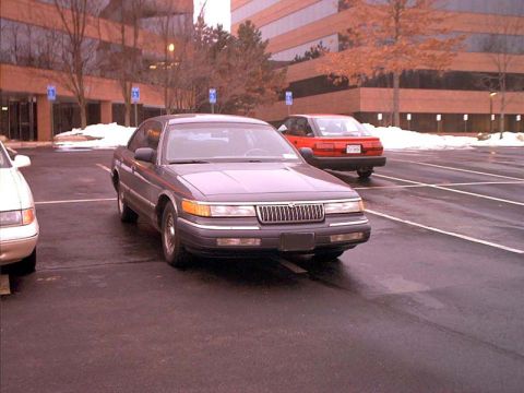 2000 Ford Crown Victoria - A gray Mercury Grand Marquis is parked in a lot with a red car visible in the background.