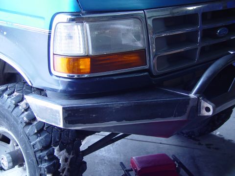 1993 Ford Bronco - Close-up of the driver's front corner of a teal and gray two-tone Ford truck showing the rectangular sealed-beam headlight with amber turn…