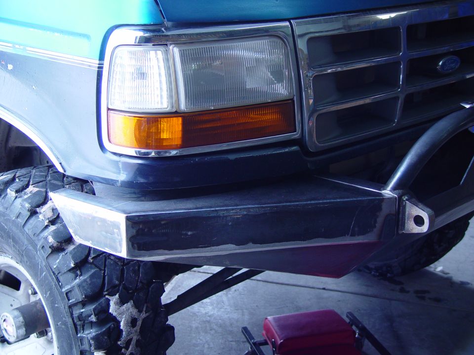 Teal Ford truck front corner with headlight, black grille and custom steel bumper with D-ring tab