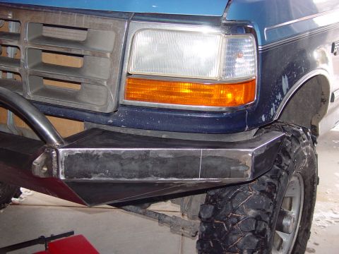 1993 Ford Bronco - Close-up of a blue Ford truck's front end, a custom-fabricated bumper and off-road tire.