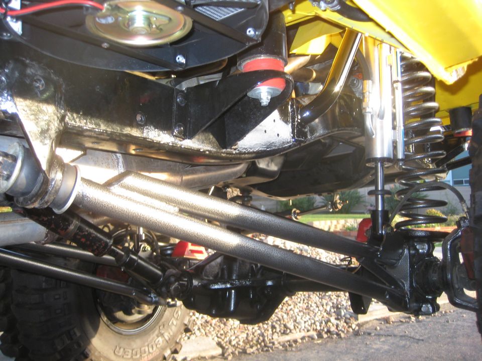Off-road vehicle suspension components including shocks, springs, and control arms. Yellow bodywork visible at top