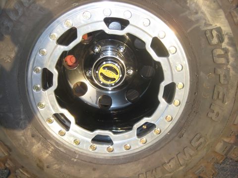 1970 Ford Bronco - A close-up view of a off-road tire and a shiny custom wheel with a prominent yellow hub cap.